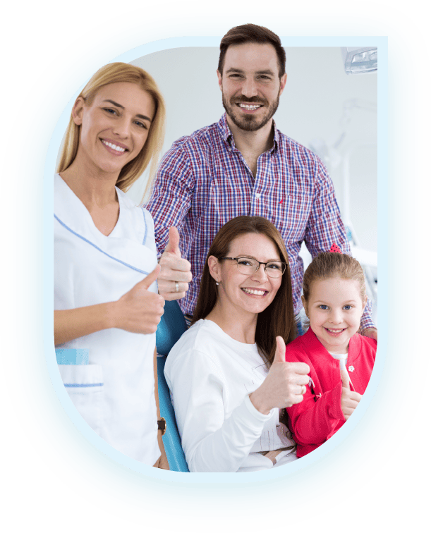 A dentist and her assistant standing with a family of three, all smiling and giving thumbs up in a dental office | Pleasant Dental